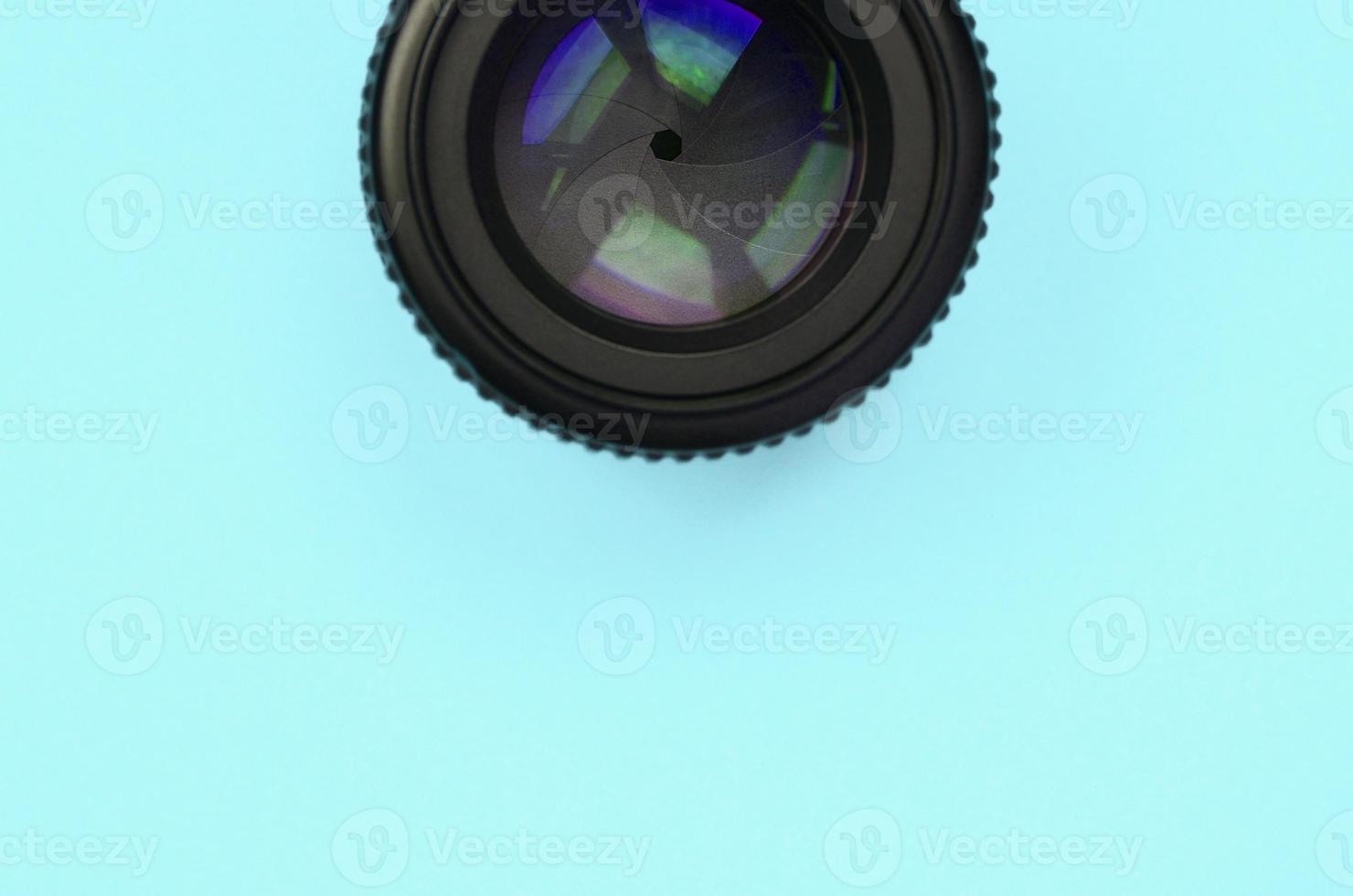 Camera lens with a closed aperture lie on texture background of fashion pastel blue color paper photo