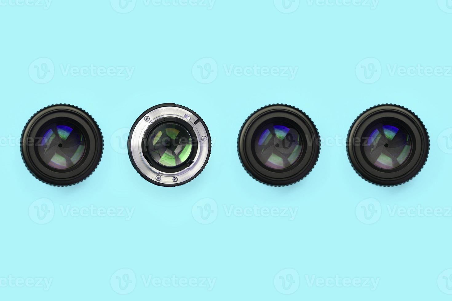 A few camera lenses with a closed aperture lie on texture background of fashion pastel blue color paper photo