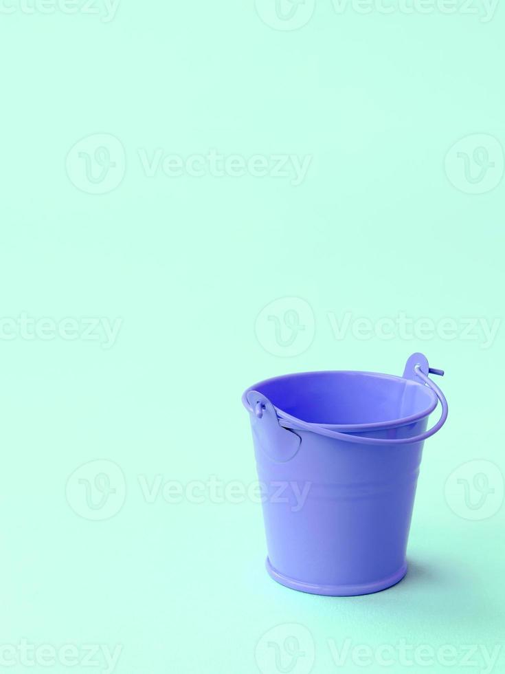 A miniature empty lilac bucket lies on a green pastel background photo