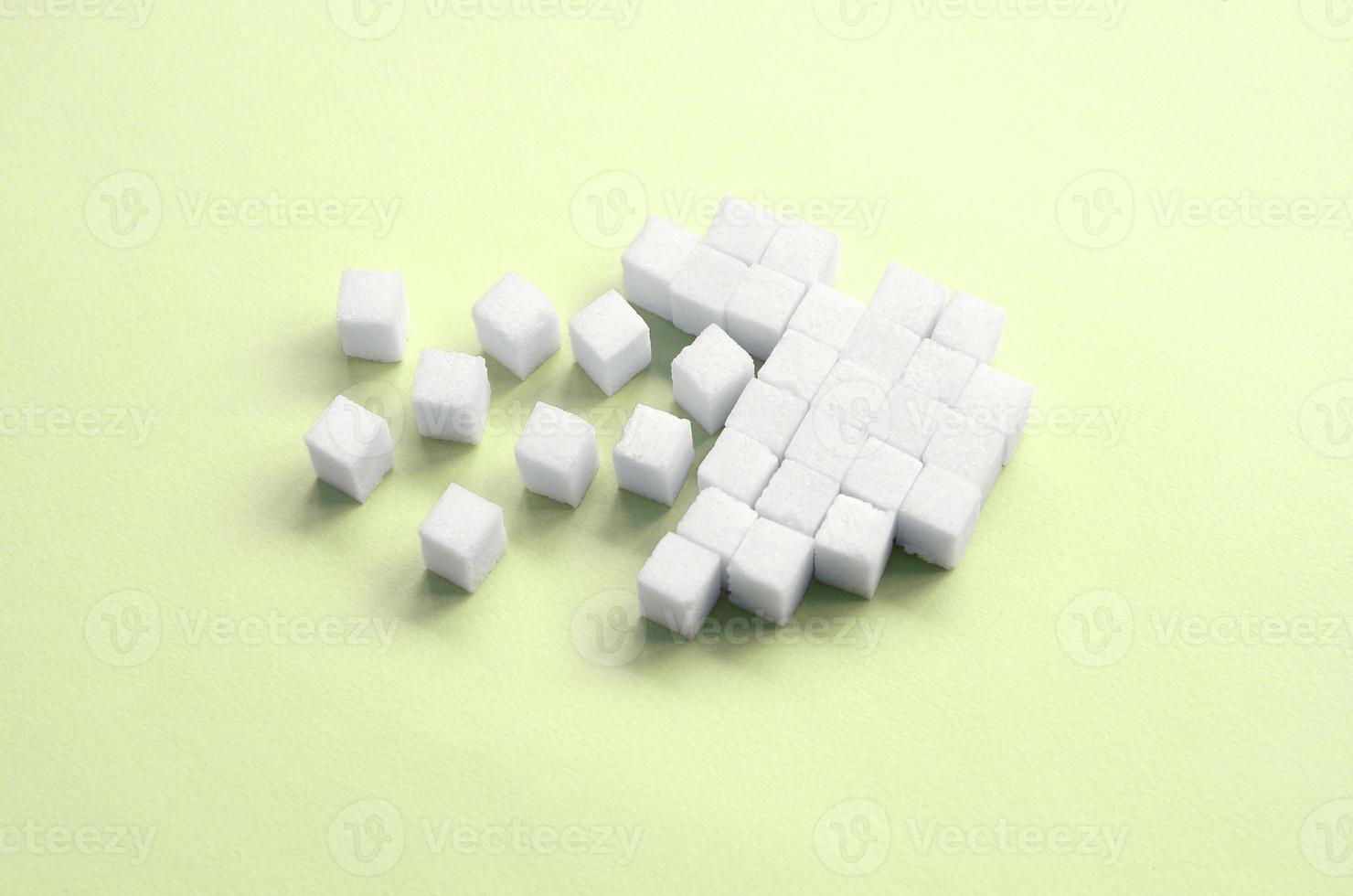 A broken heart made of sugar cubes lies on a trendy pastel lime photo