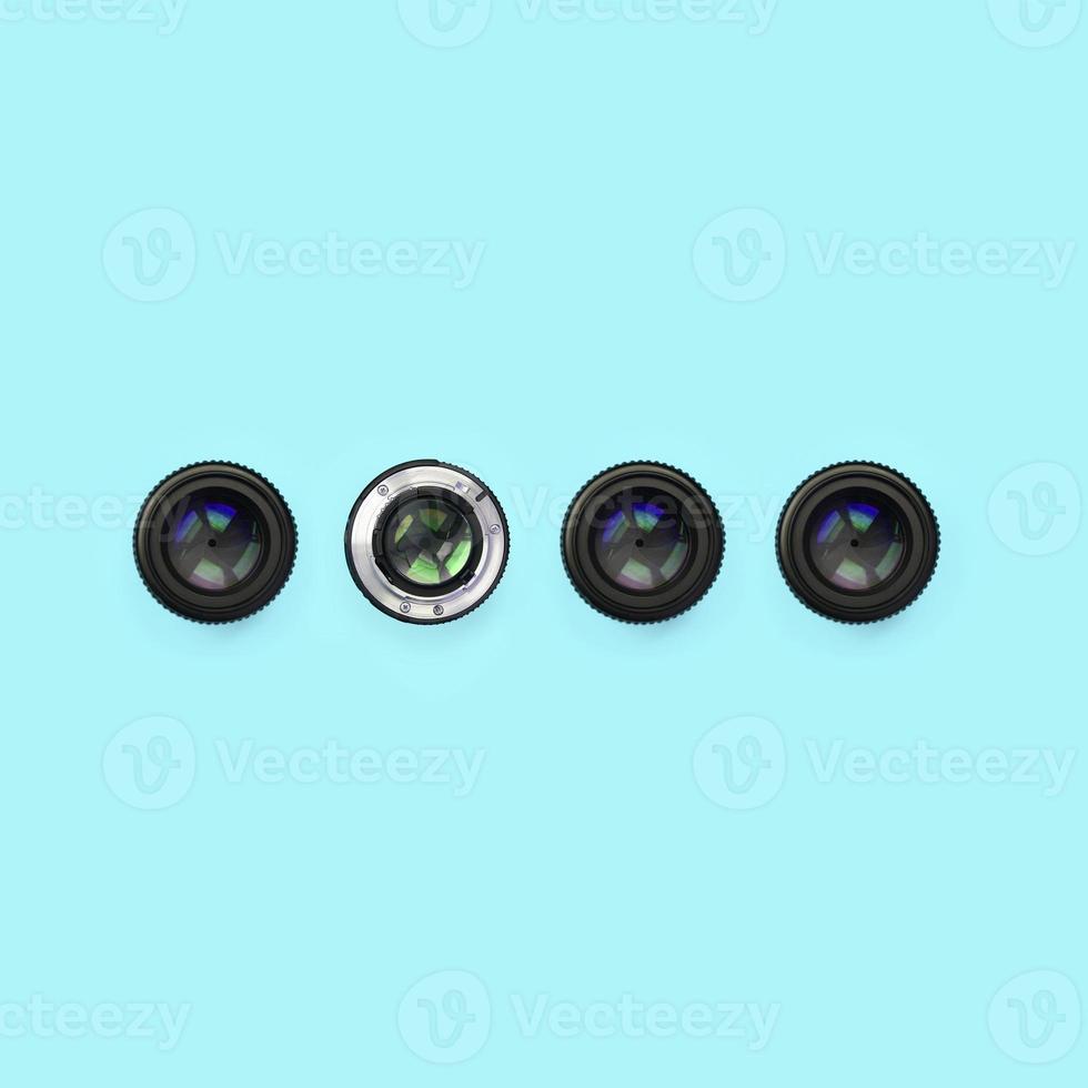 A few camera lenses with a closed aperture lie on texture background of fashion pastel blue color paper photo