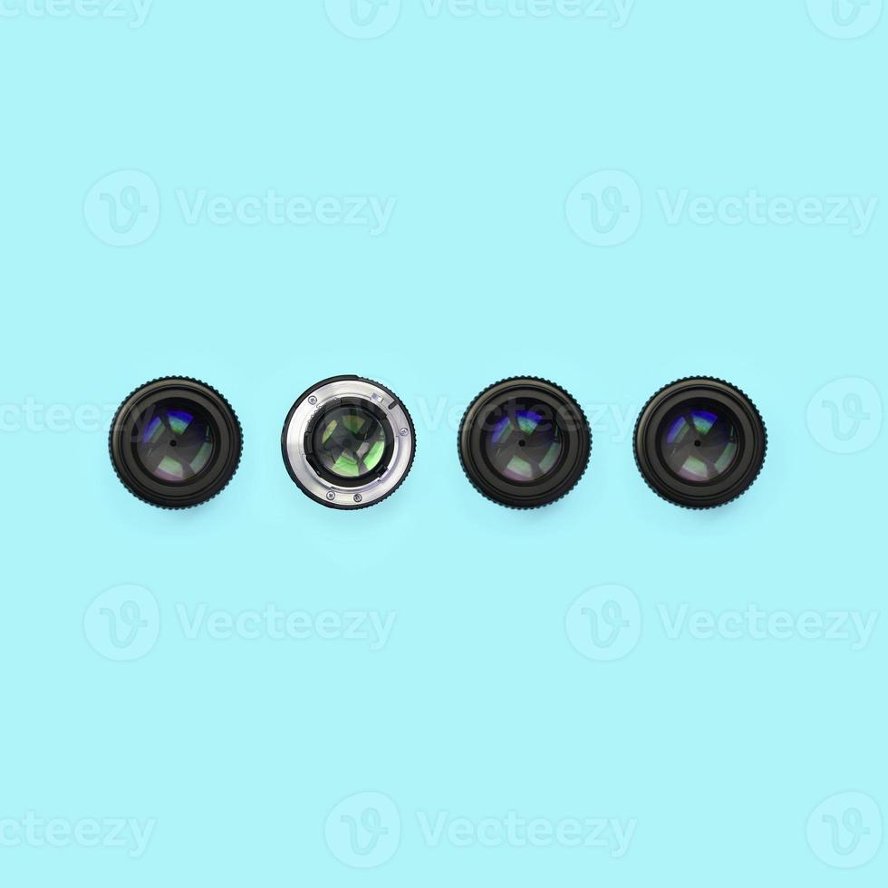 A few camera lenses with a closed aperture lie on texture background of fashion pastel blue color paper photo