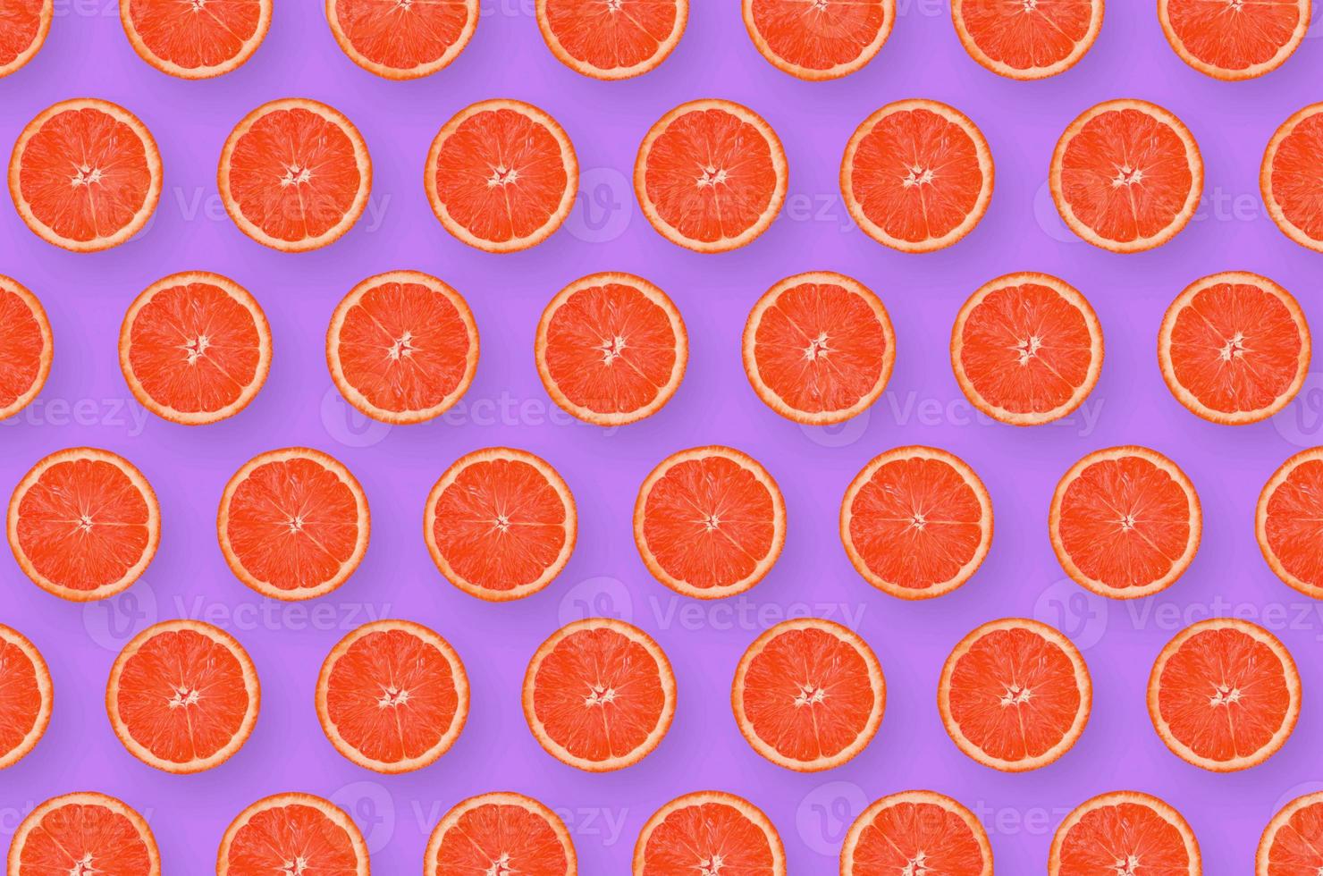 Pattern of grapefruit citrus slices on bright purple background photo