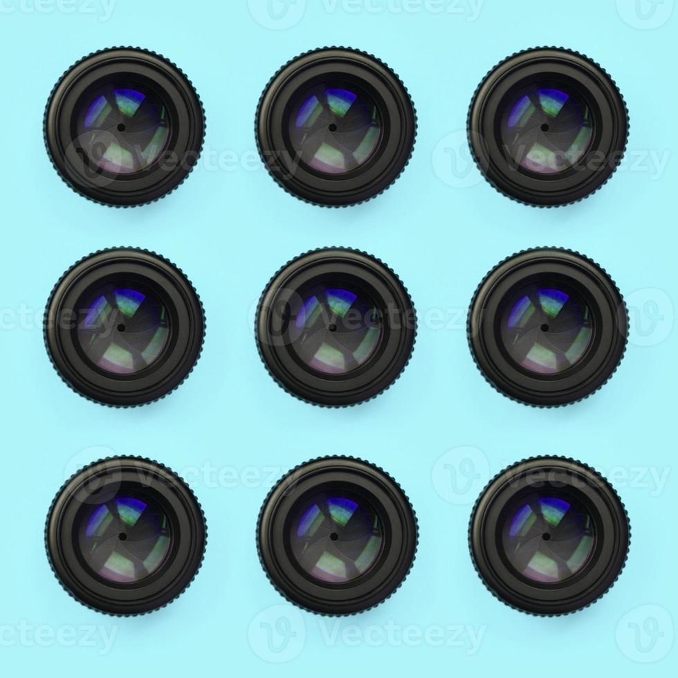 A few camera lenses with a closed aperture lie on texture background of fashion pastel blue color paper photo