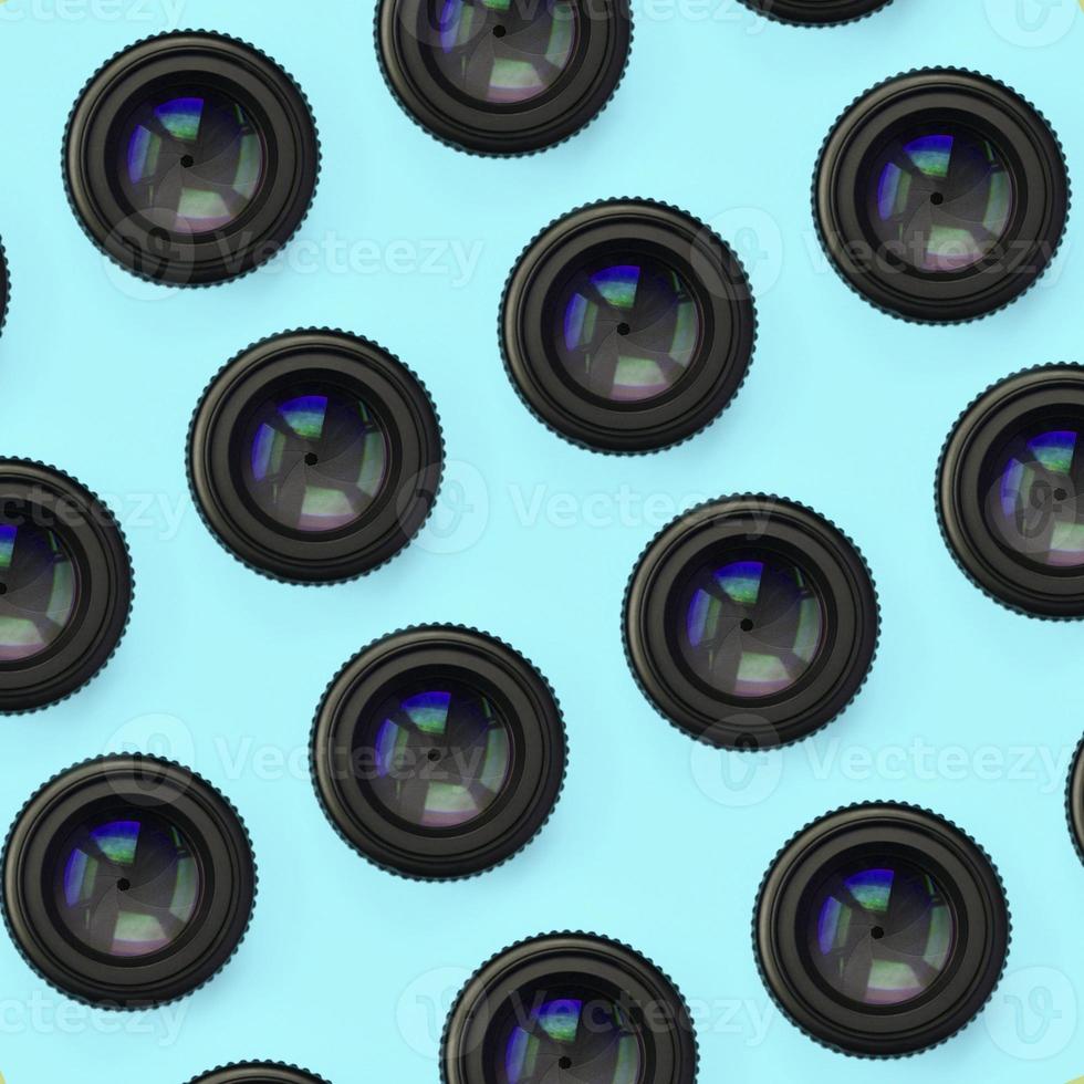 A few camera lenses with a closed aperture lie on texture background of fashion pastel blue color paper photo