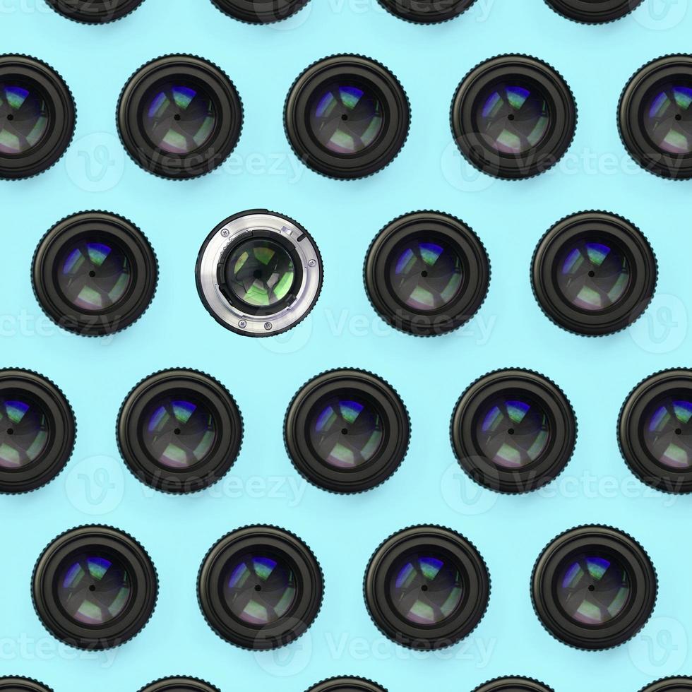 A few camera lenses with a closed aperture lie on texture background of fashion pastel blue color paper photo