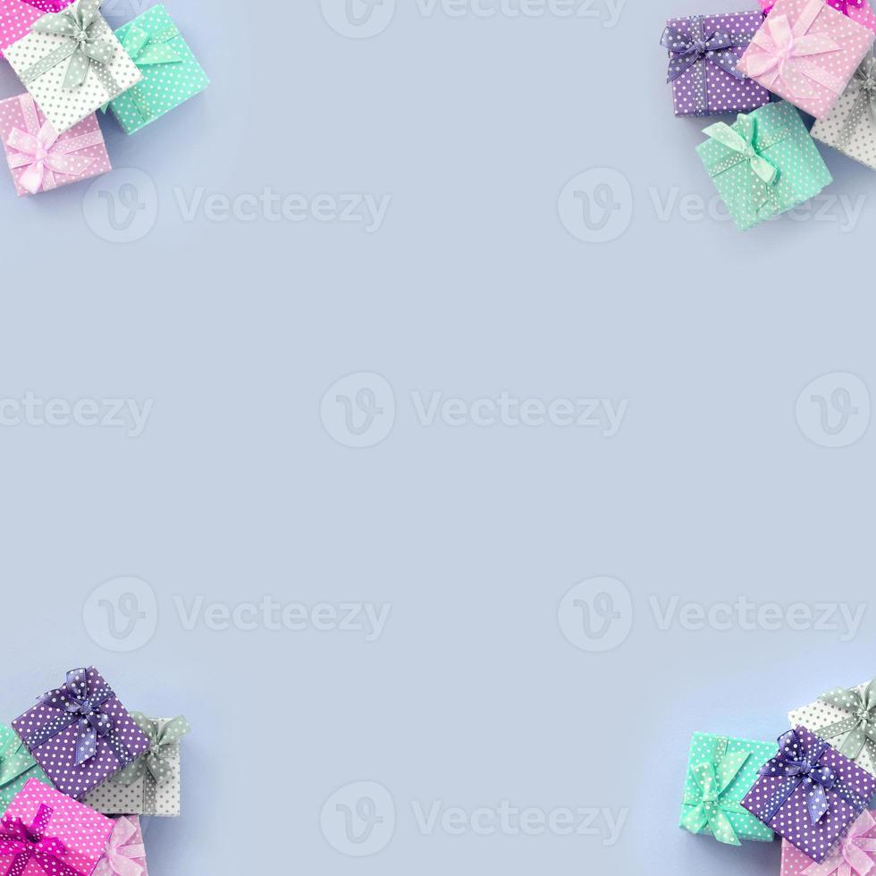 Piles of a small colored gift boxes with ribbons lies on a violet background photo