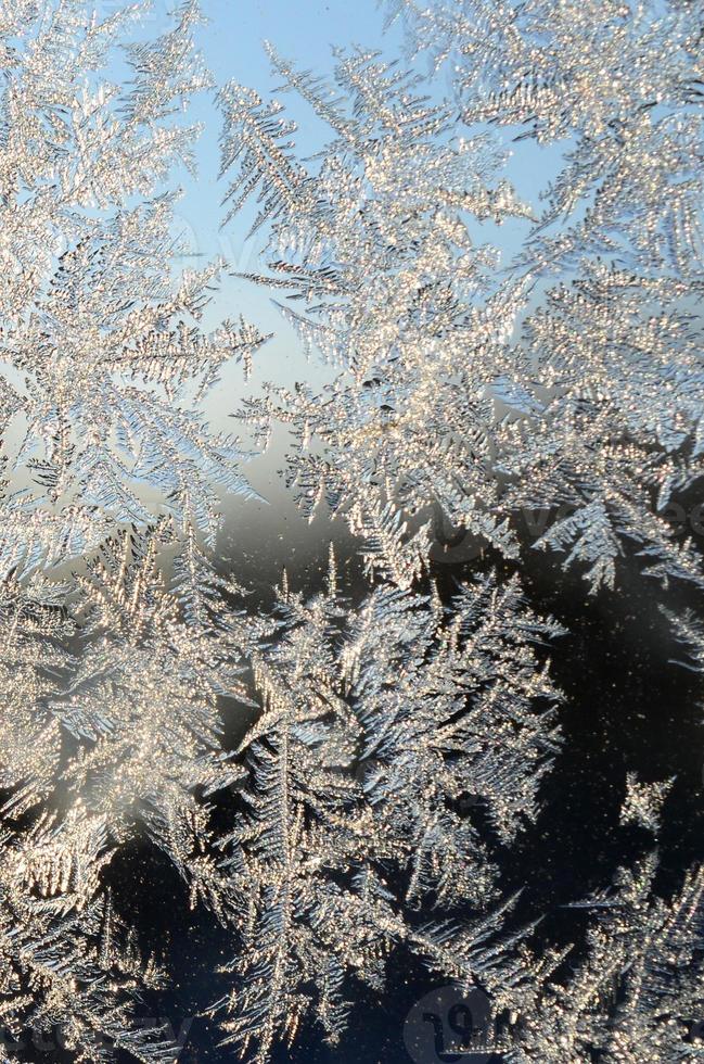 Snowflakes frost rime macro on window glass pane photo