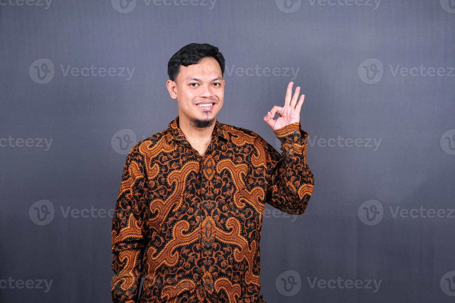 positive attractive asian man showing ring gesture with fingers.close up portrait, good job, agreement concept. I am OK, approval. guy being satisfied with suggestion. Isolated on gray background photo