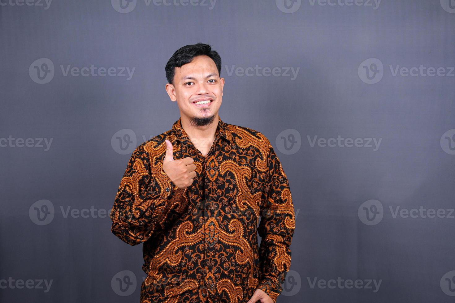 portrait of young asian guy in a batik posing isolated on gray background photo