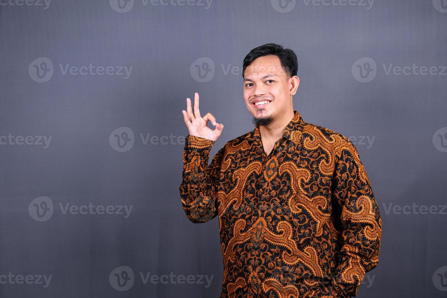 positive attractive asian man showing ring gesture with fingers.close up portrait, good job, agreement concept. I am OK, approval. guy being satisfied with suggestion. Isolated on gray background photo