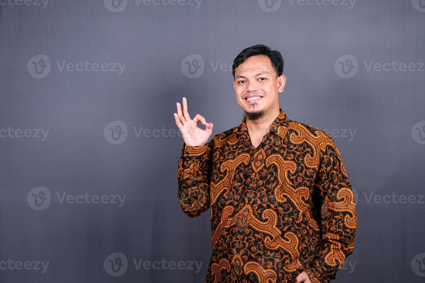 positive attractive asian man showing ring gesture with fingers.close up portrait, good job, agreement concept. I am OK, approval. guy being satisfied with suggestion. Isolated on gray background photo
