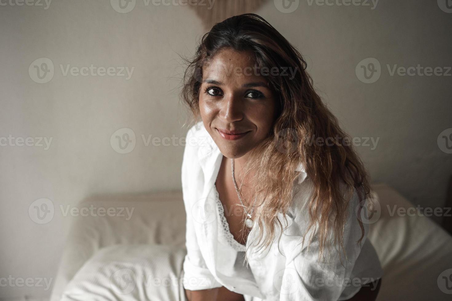 Portrait of a beautiful Latina woman lying on her bed in the morning. photo