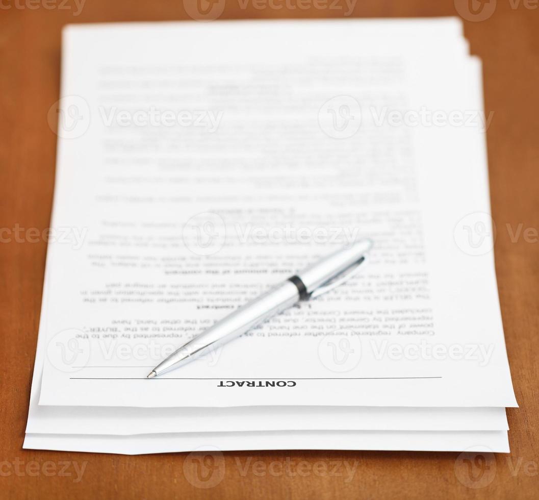 sheets of contract and silver pen on wooden table photo