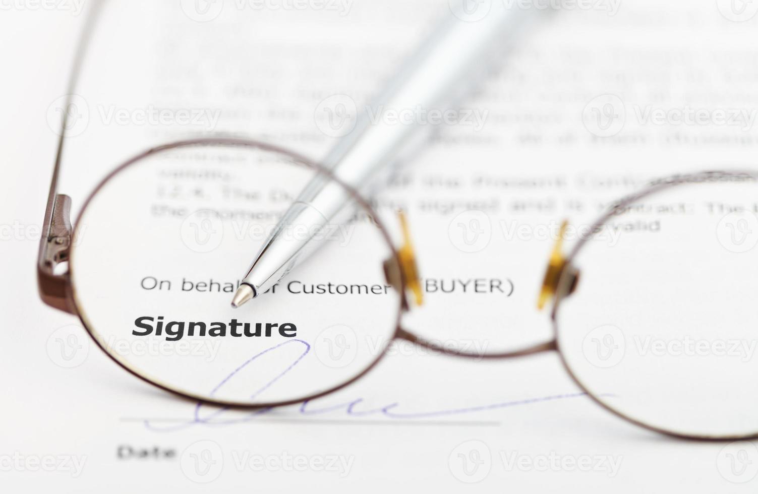 signature of contract and pen through eyeglasses photo