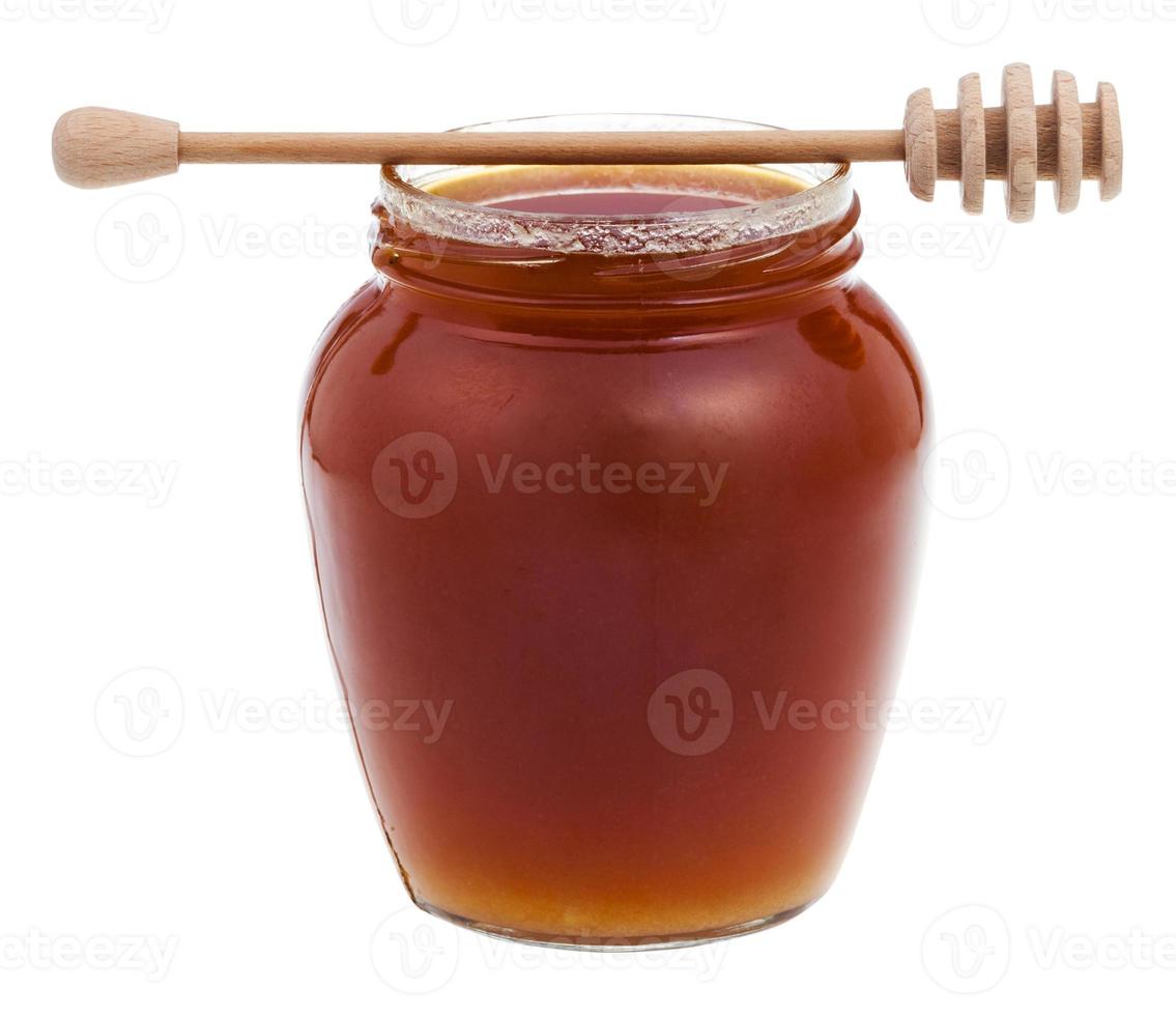 side view glass jar with honey and wooden stic photo