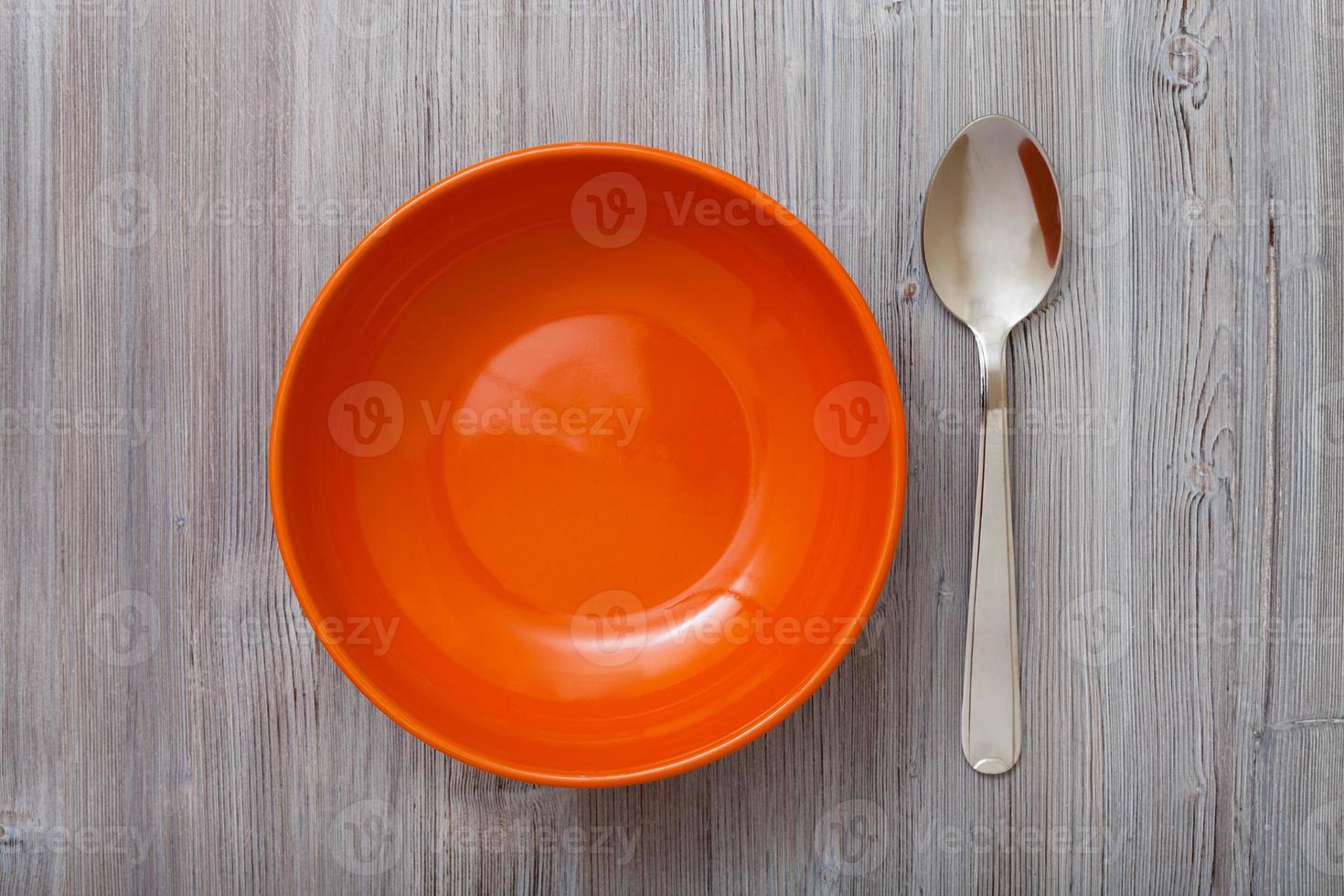 vista superior tazón naranja y cuchara en mesa marrón gris foto