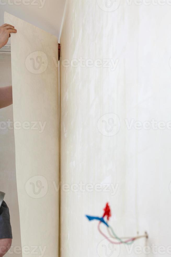 decorator fixes wallpaper on wall in house photo