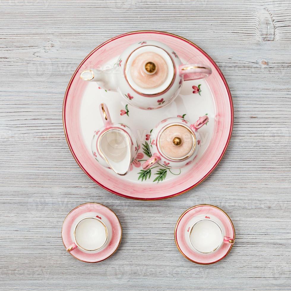 juego de té de porcelana rosa sobre tablón marrón gris foto