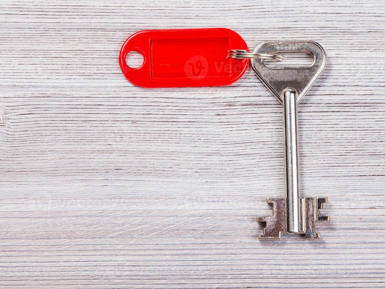 big door key with red key chain on wooden board photo