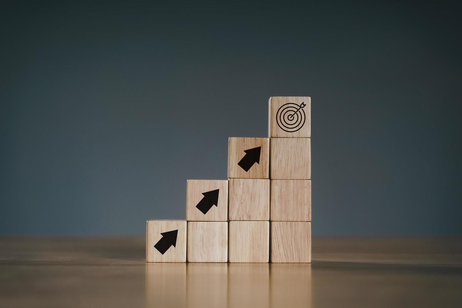 pila de bloques de cubo de madera como escalón en la mesa de madera. éxito, escalar a la cima, progresión, concepto de crecimiento empresarial. foto