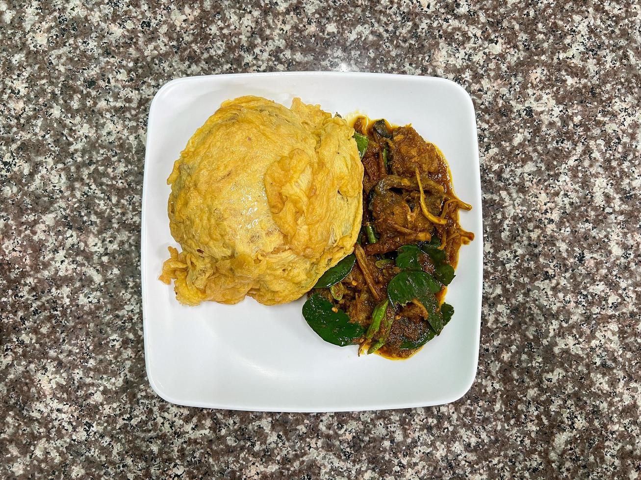 Rice topped with curry, spicy stir-fried catfish, a food that is easy to find in Thailand photo