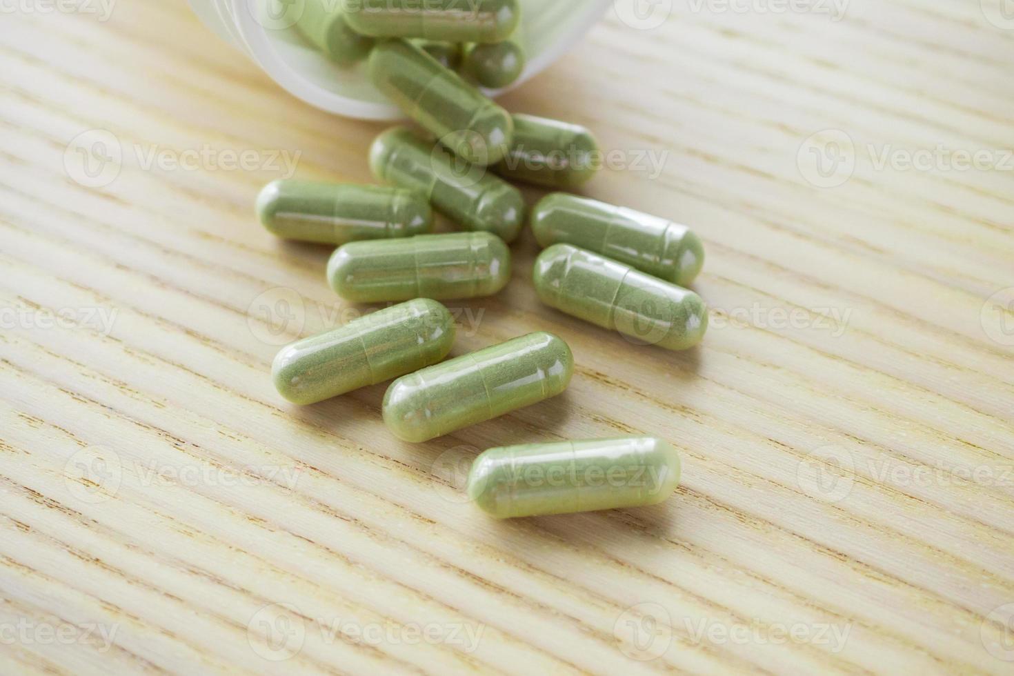 Herbal medicine capsules with bottle on wood table photo
