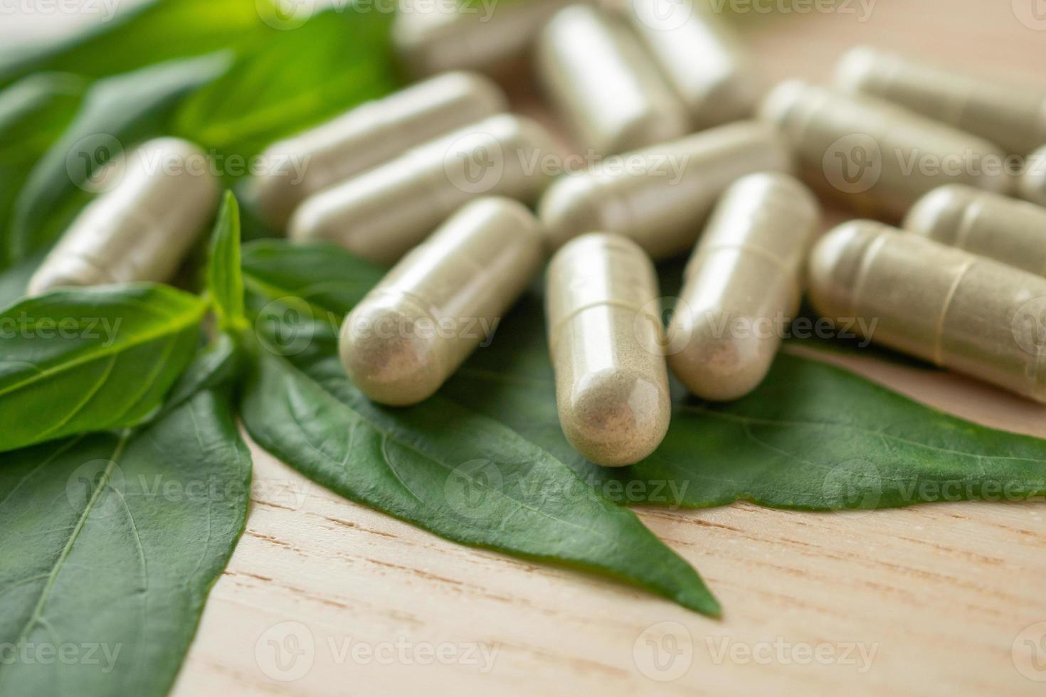 Herbal medicine capsules with Andrographis paniculata leaf on wood table photo