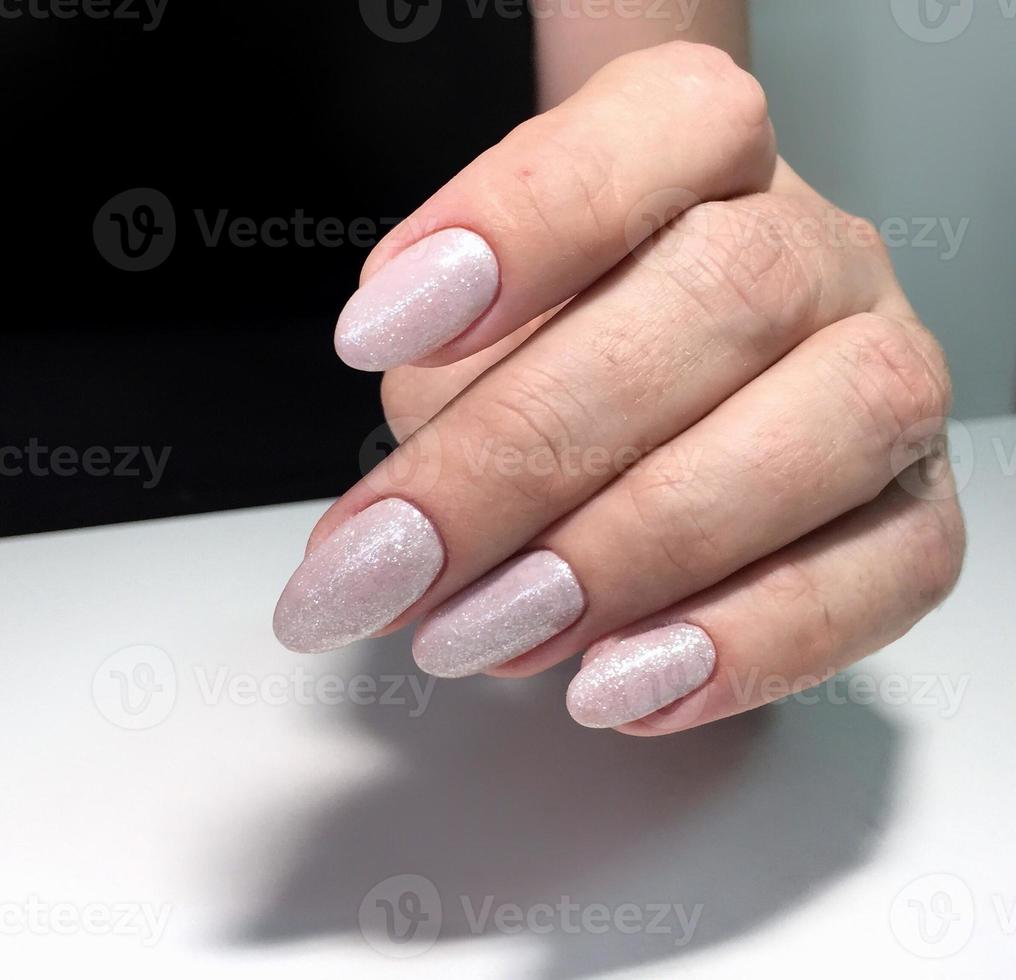 Female white manicure on nails against a dark background photo