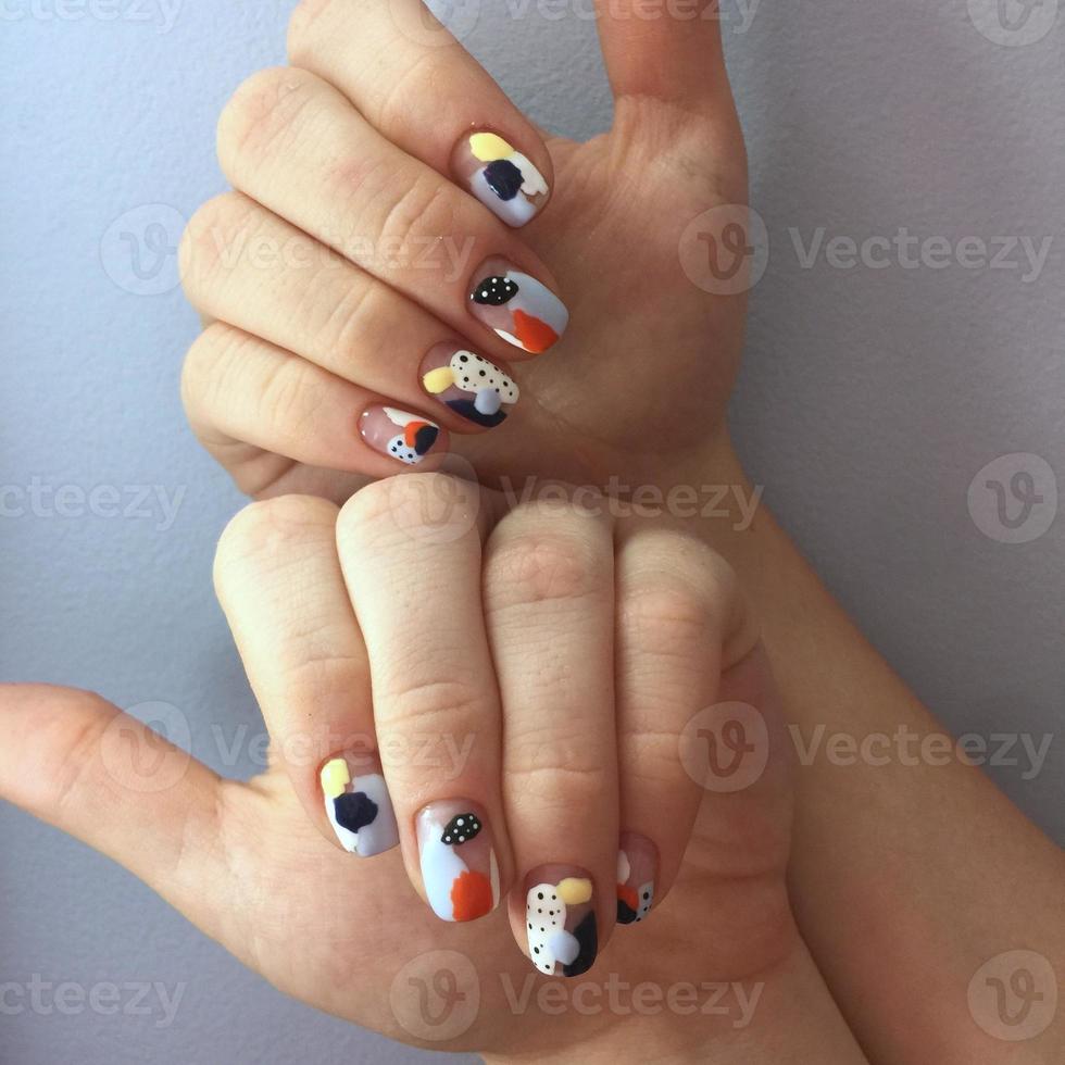 Manicure of different colors on nails. Female manicure on the hand on blue background photo