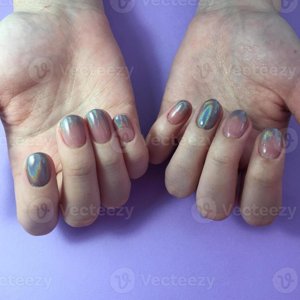 Manicure of different colors on nails. Female manicure on the hand on blue background photo