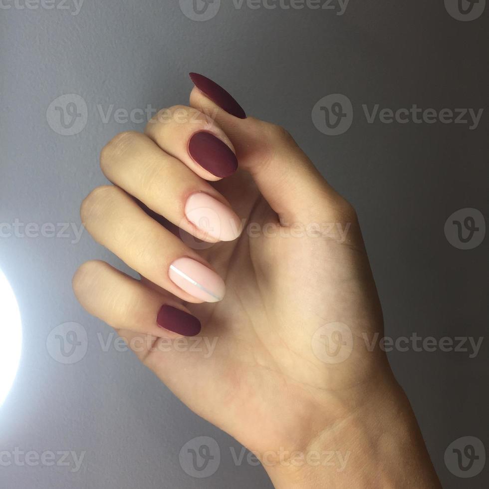 Closeup of hands of a young woman with pink and red manicure on nails photo