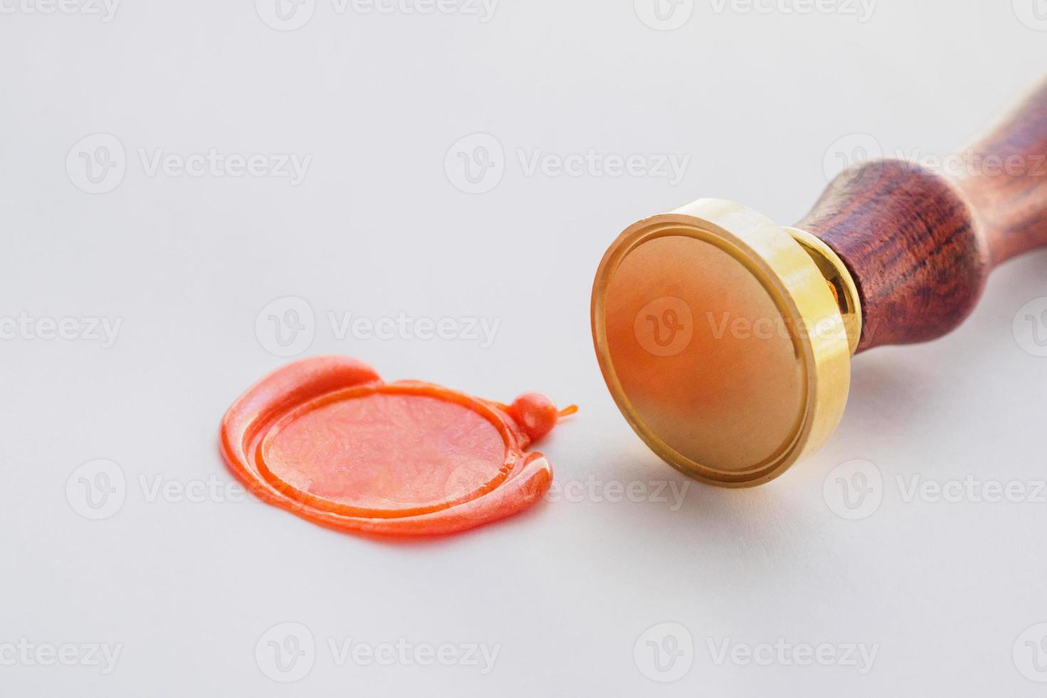 metal head stamp tool with wooden handle and wax seal on white paper photo