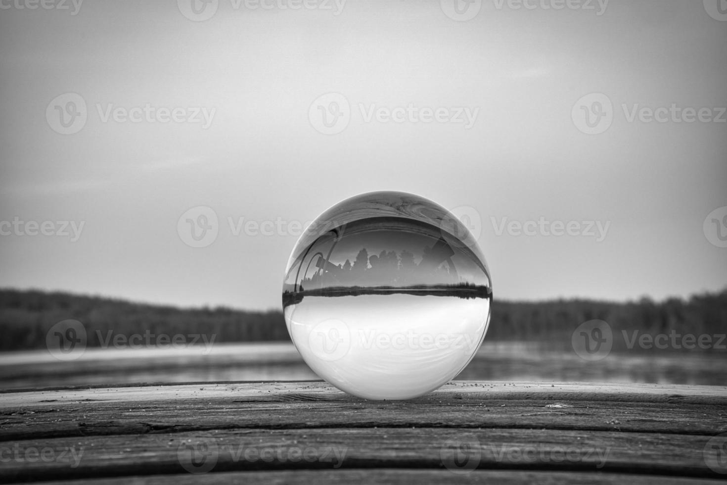 Glass ball on a wooden pier at a Swedish lake at dusk in black and white. Nature photo