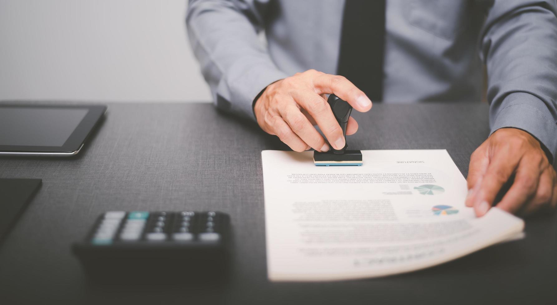 Businessman validates and manages business documents and agreements, signing a business contract approval of contract documents confirmation or warranty certificate,approval stamp photo