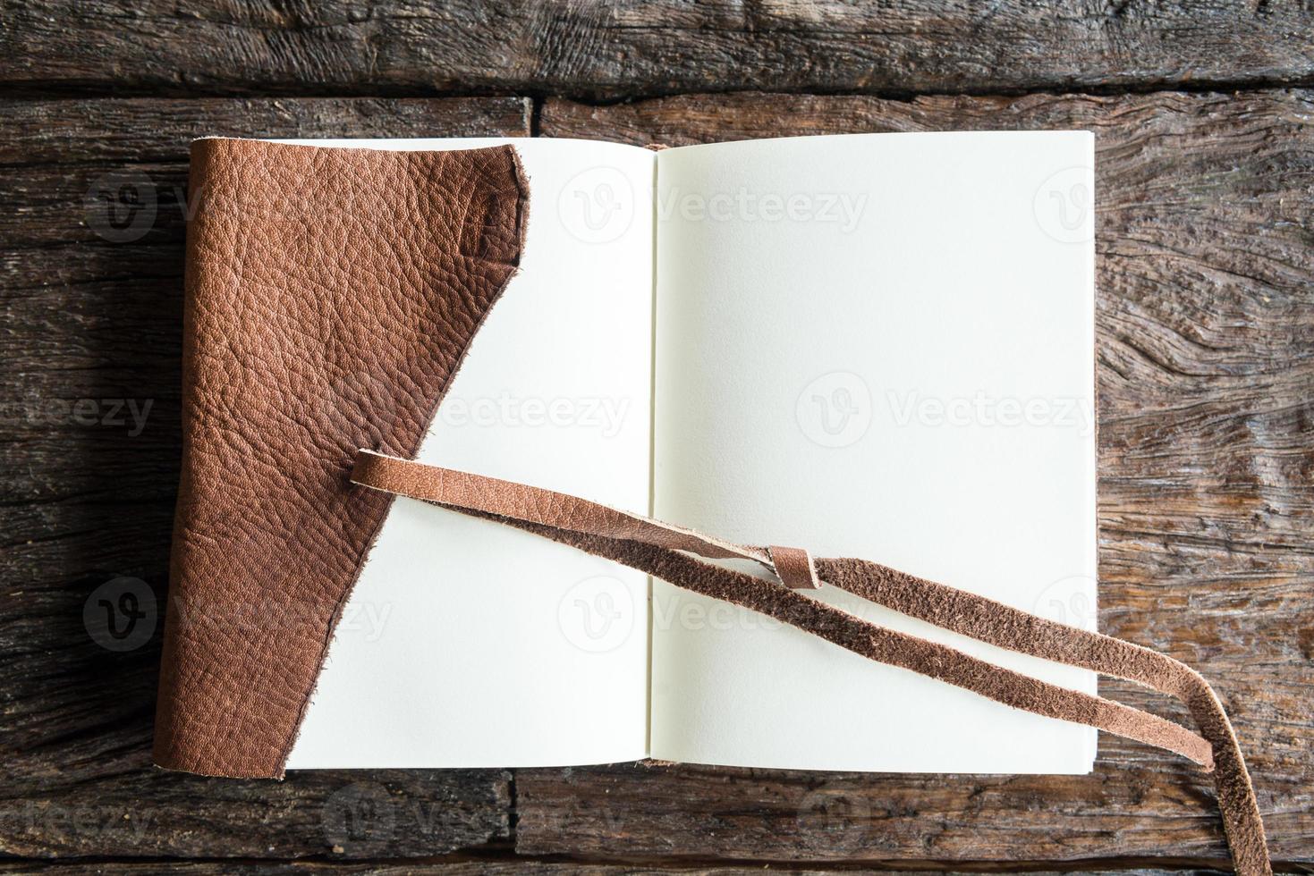 An opened diary leather book with blank space on the wood table. The education and learning concept. photo