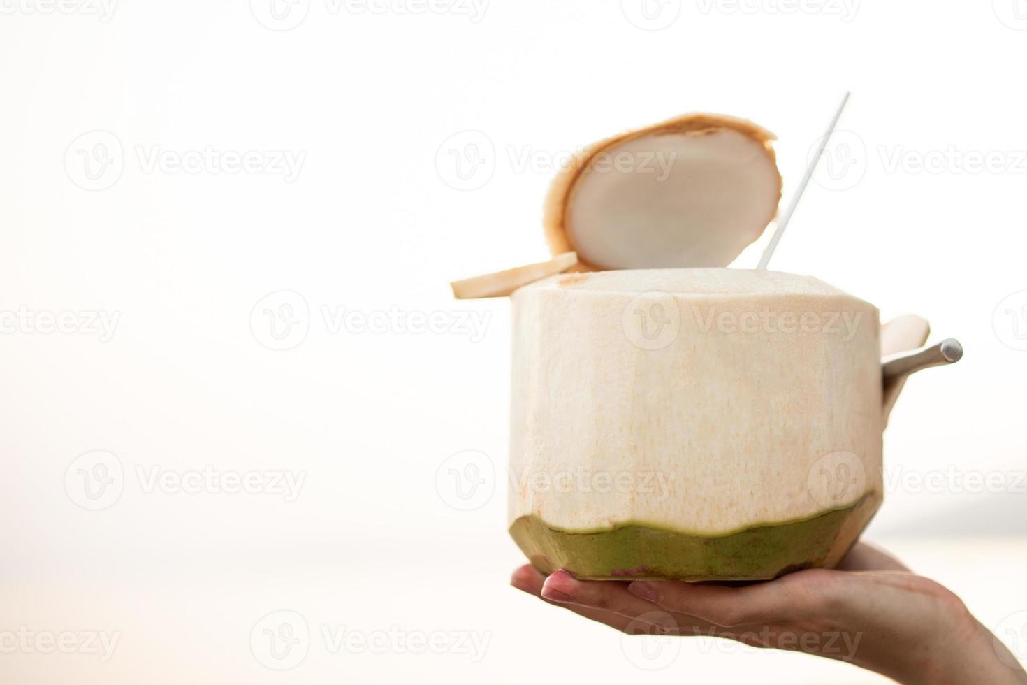 Hand holding fresh coconut on the beach, romantic sunset moment. summer vacation. photo