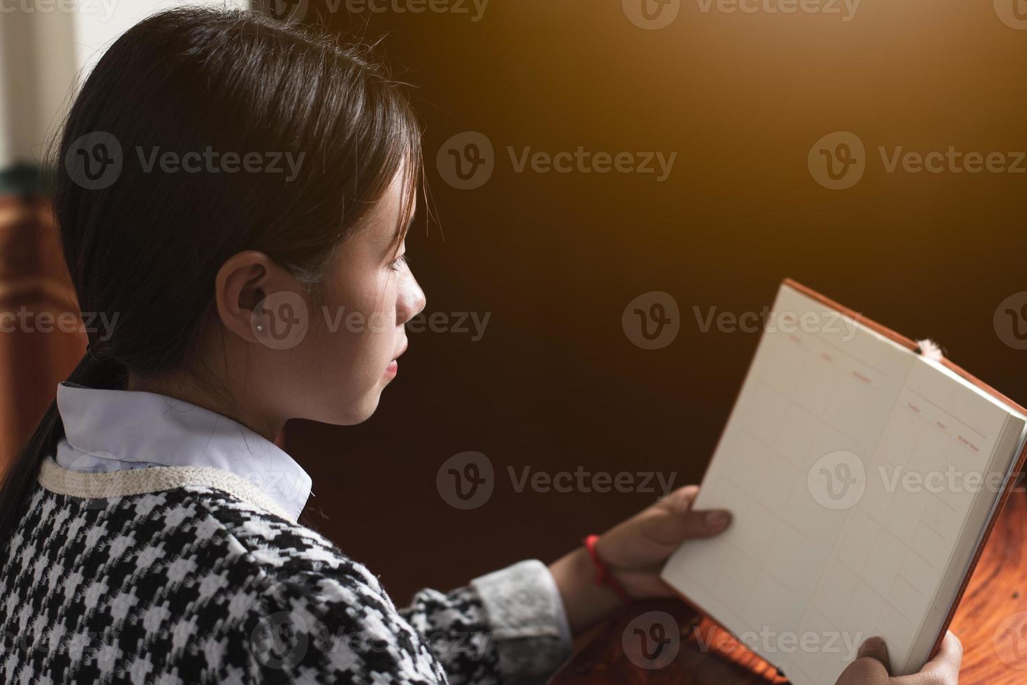 un joven estudiante está leyendo un libro escolar para aprender y prepararse para el examen y la tarea en la mesa, concepto de educación y estudio, espacio de copia de tiro trasero para texto individual foto