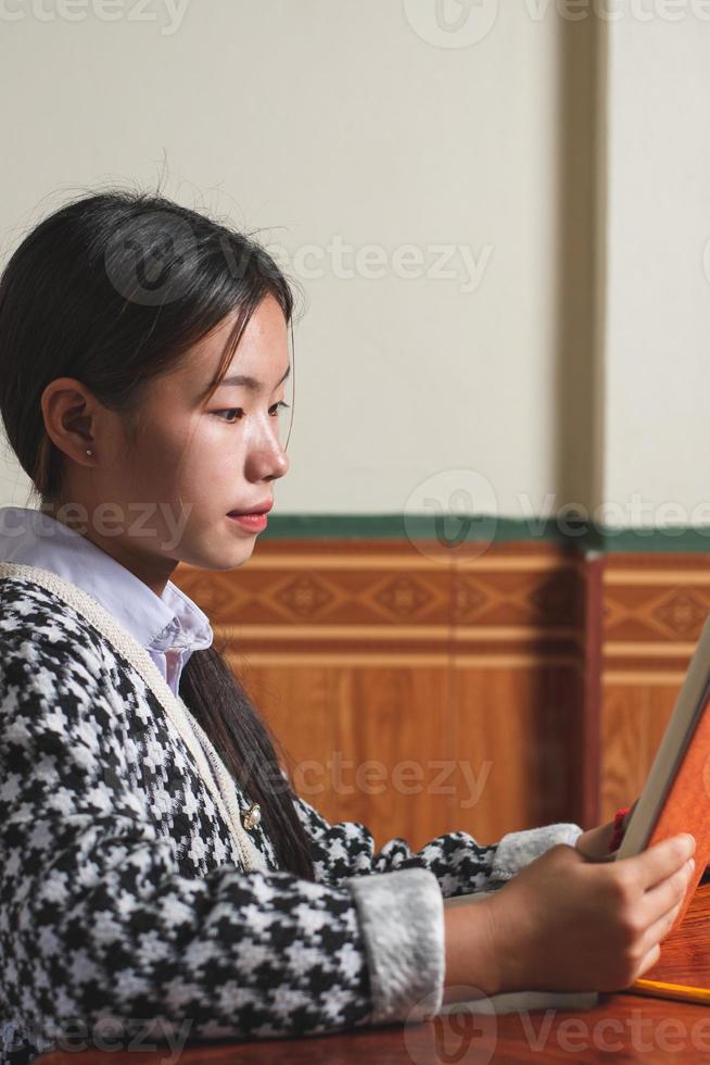 Portrait shot of young student is reading a school book for learning and prepare for exam and homework on the table, education and study concept, backside shot copy space for individual text photo