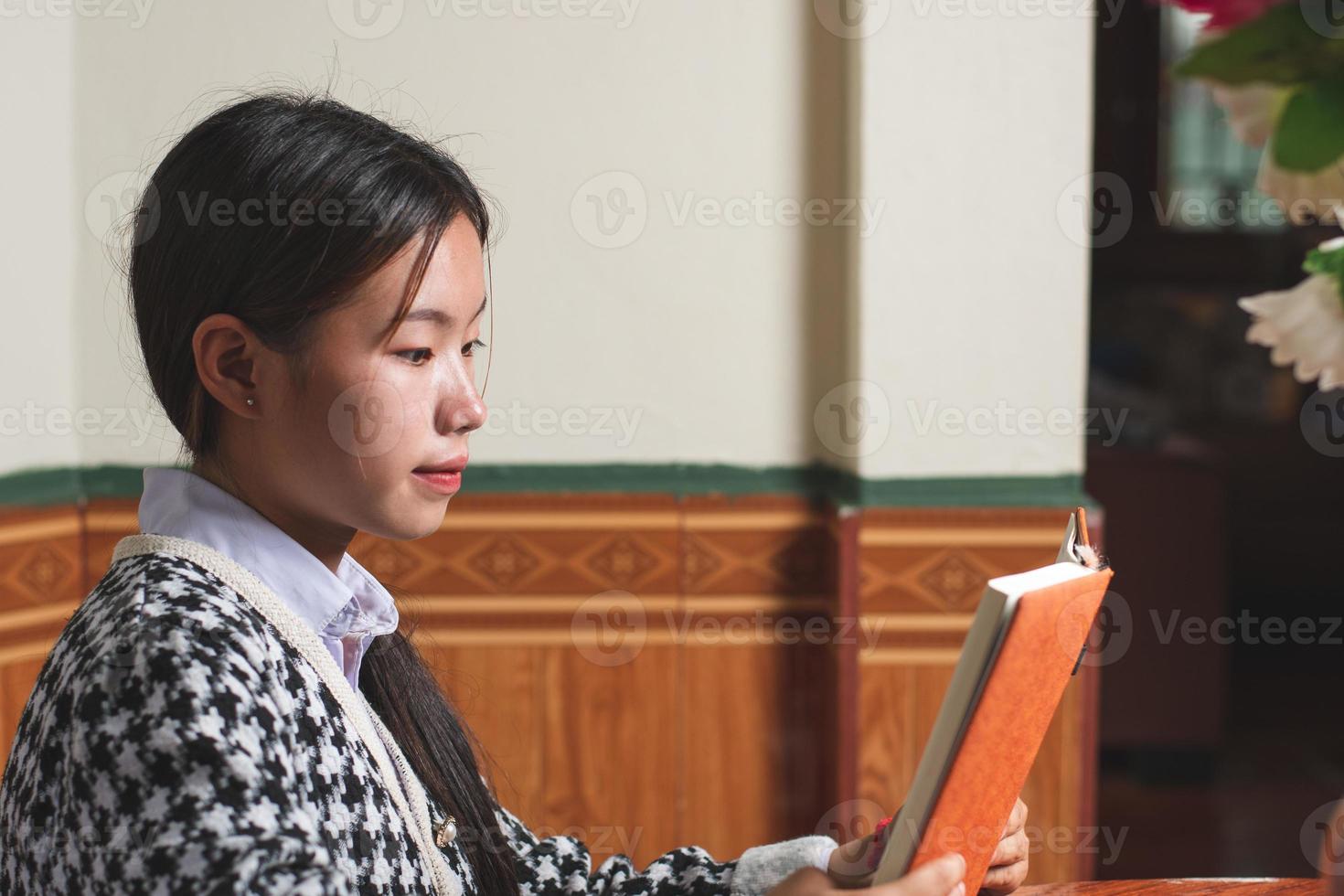 A young student is reading a school book for learning and prepare for exam and homework on the table, education and study concept, backside shot copy space for individual text photo