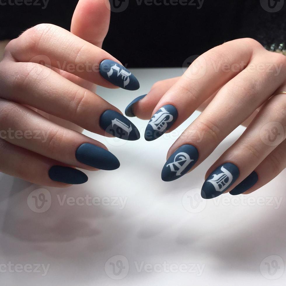 Woman with flesh-colored manicure with design and the inscription BAD, close up photo