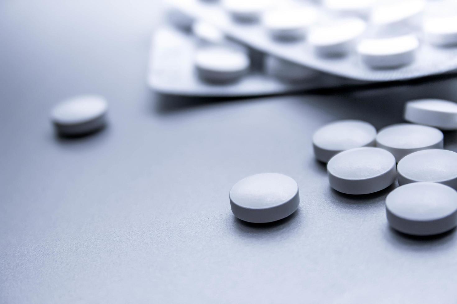 White medical pills are spread on the gray table. photo