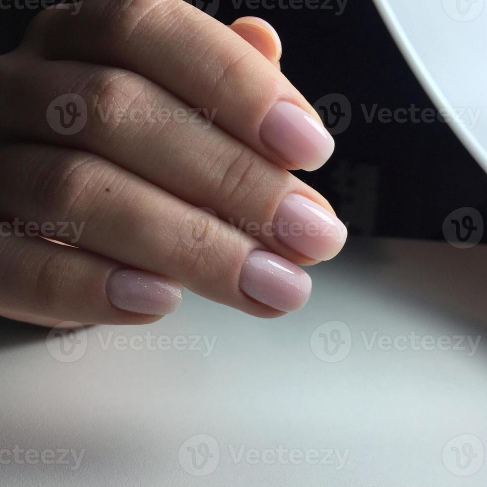 elegante manicura rosa femenina de moda. manos de una mujer con manicura rosa en las uñas foto