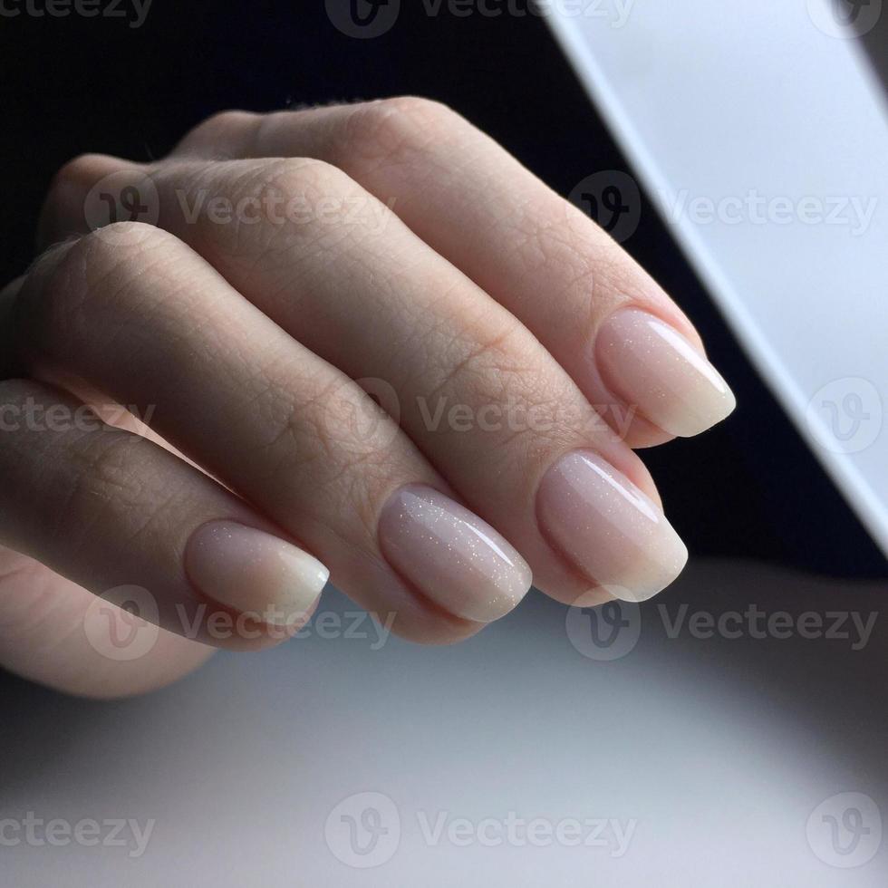 Woman's hands with white nails on the dark background photo