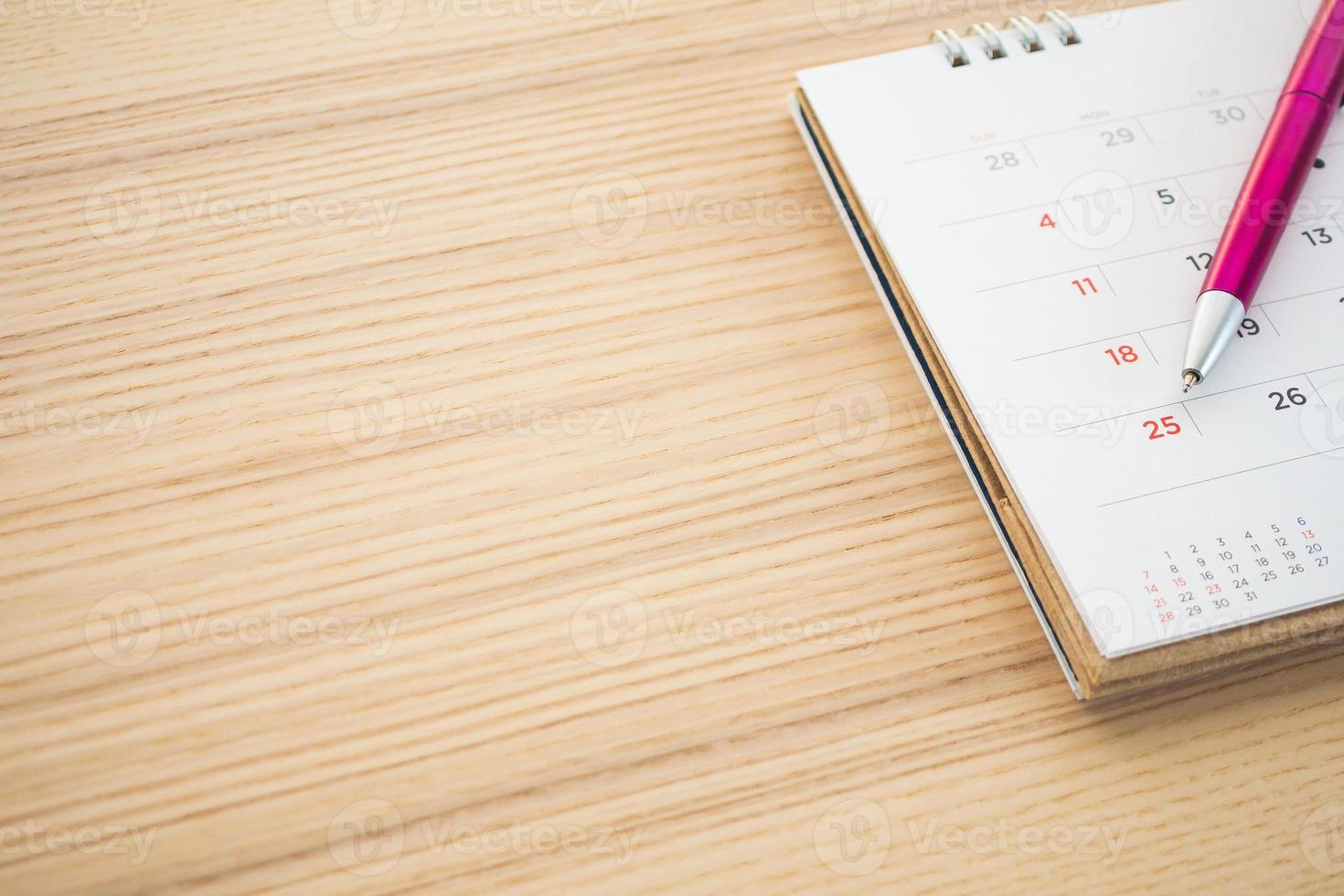 calendar page with pen point at 25th date on wood table background photo