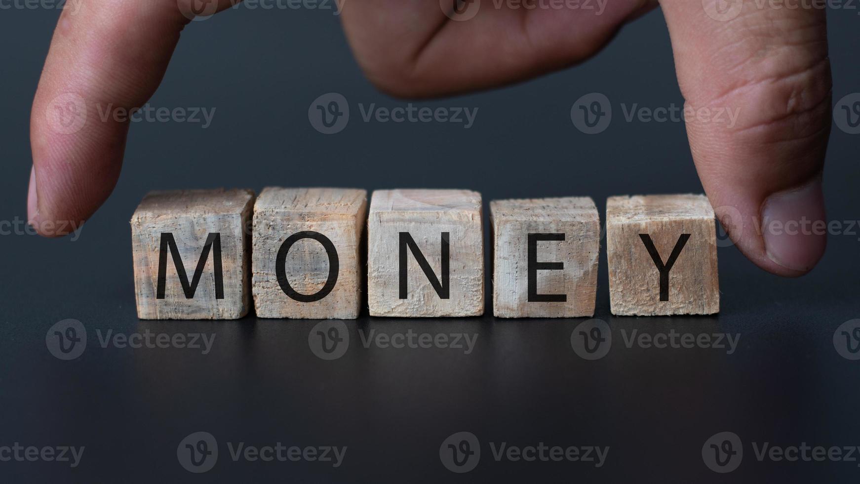 A hand catching the wooden box with money text on the black background, money bank and finance concept photo