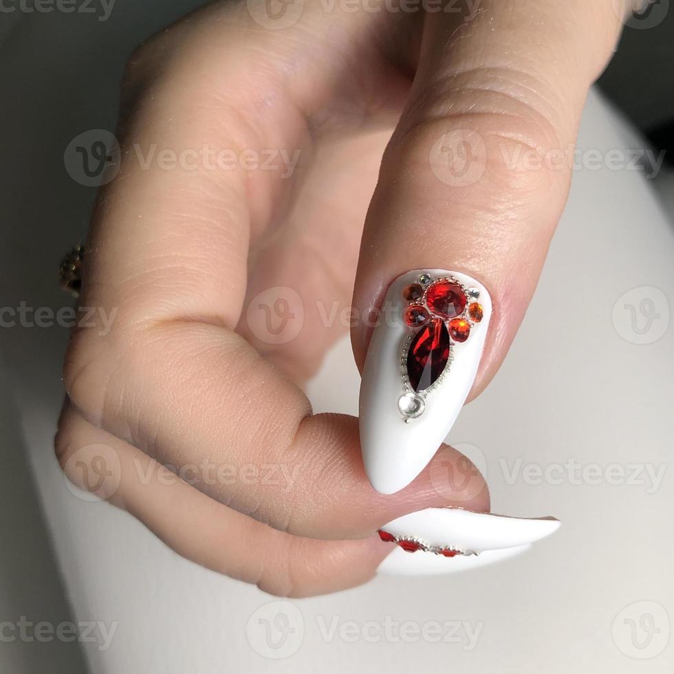 elegante manicura blanca femenina de moda con diseño.manos de una mujer con manicura blanca en las uñas foto