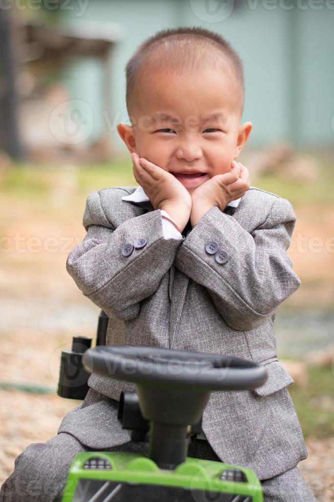 A smile children sitting on his toy car, close up shot with blur background photo