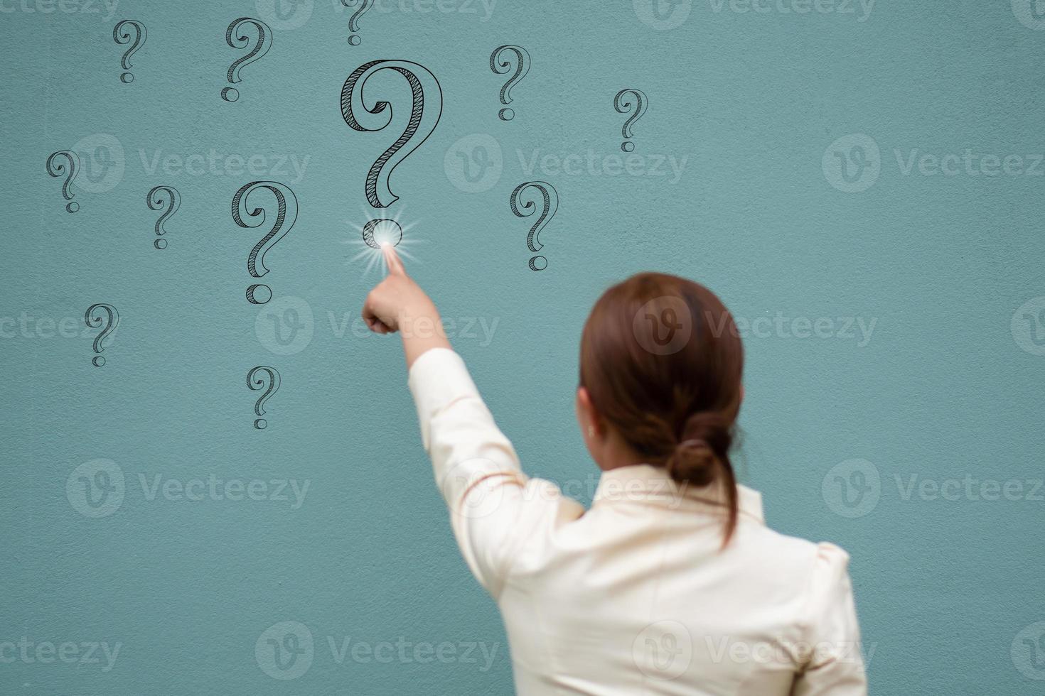 A business women touch question mark on the blue wall, question and answer concept focus on the wall photo