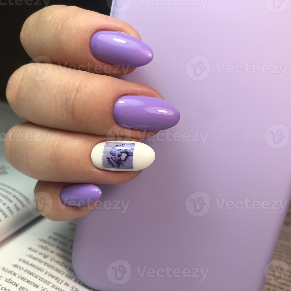 elegante manicura púrpura femenina de moda con diseño.manos de una mujer con manicura púrpura en las uñas foto